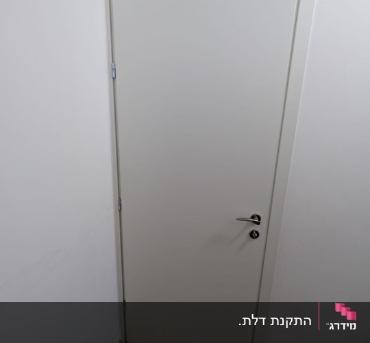 דלת פנים לבנה מותקנת עם משקוף תואם, ידית מתכת ורצפת פרקט